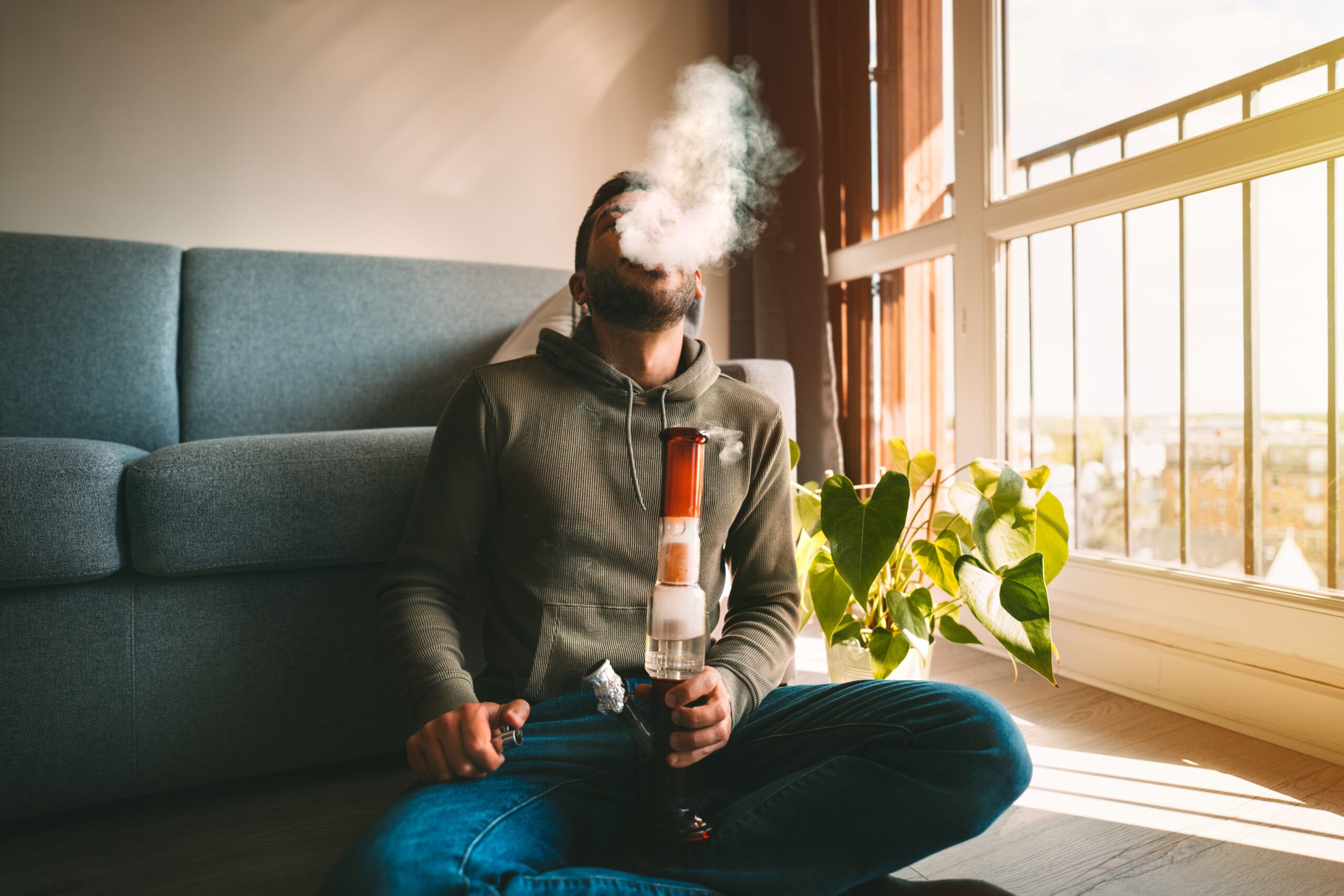 responsible cannabis use - man smoking bong and exhaling in his home